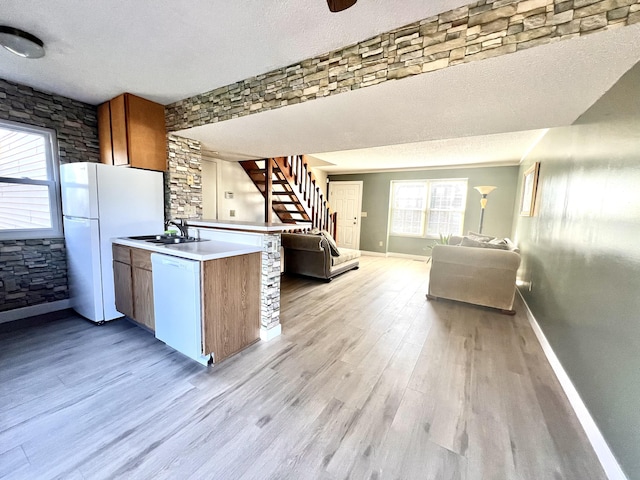 kitchen with a textured ceiling, white appliances, light hardwood / wood-style flooring, and sink