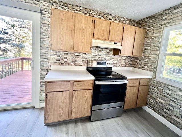 kitchen featuring a textured ceiling, light hardwood / wood-style floors, extractor fan, and stainless steel range with electric cooktop