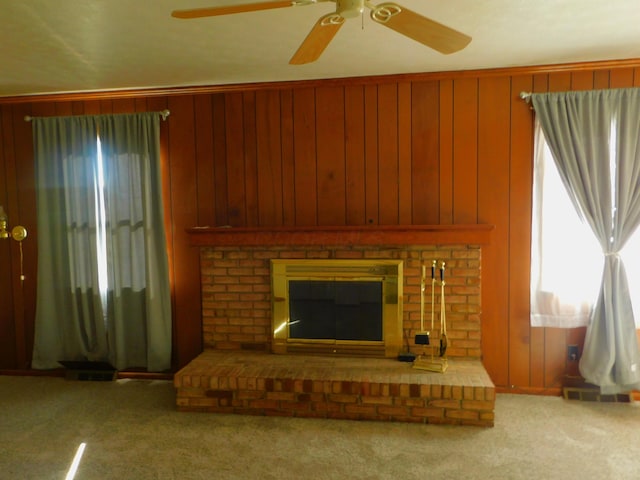 carpeted living room featuring wood walls, ceiling fan, and a brick fireplace