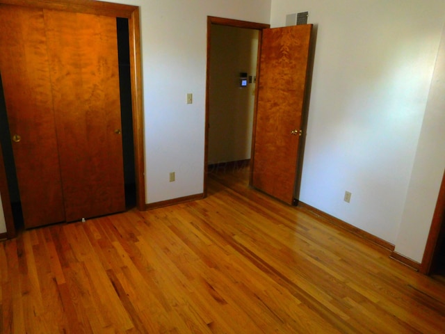 unfurnished bedroom with a closet and light wood-type flooring