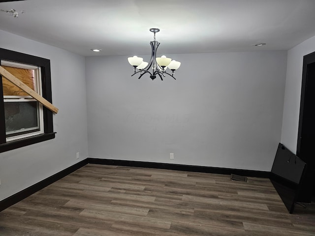 spare room featuring a chandelier and dark hardwood / wood-style flooring