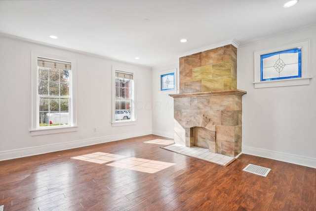 unfurnished living room featuring crown molding, wood-type flooring, and a tile fireplace