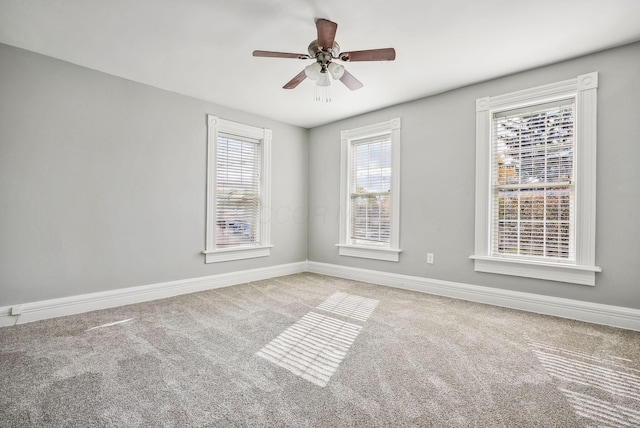 empty room featuring ceiling fan, light colored carpet, and a wealth of natural light