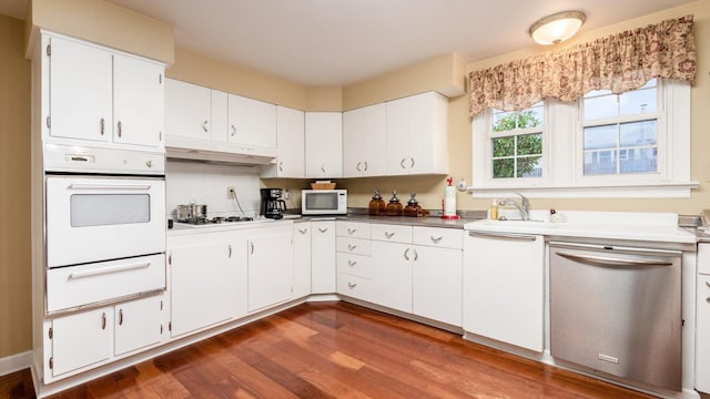 kitchen featuring dark hardwood / wood-style flooring, white appliances, white cabinetry, and sink