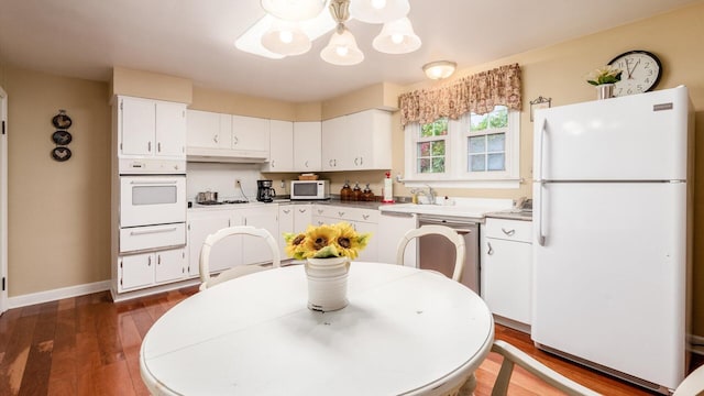 kitchen featuring appliances with stainless steel finishes, dark hardwood / wood-style flooring, sink, a chandelier, and white cabinetry