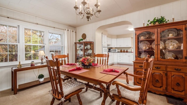 carpeted dining area featuring wooden walls and an inviting chandelier