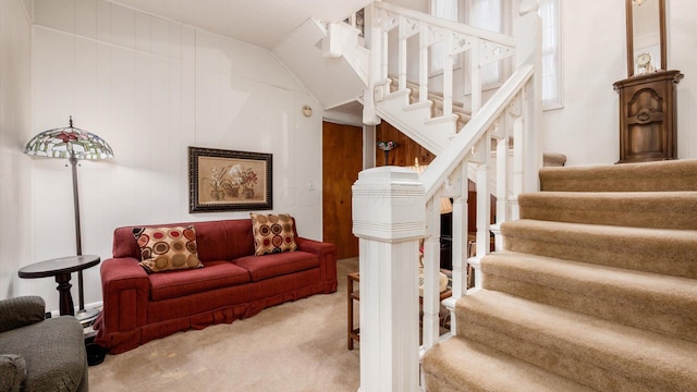 staircase featuring carpet, wood walls, and lofted ceiling