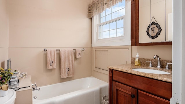 bathroom featuring a washtub, vanity, and toilet