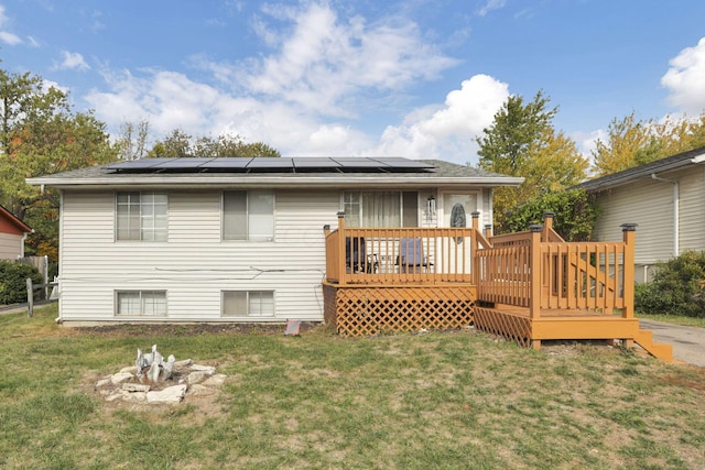 rear view of property featuring solar panels, a yard, and a deck