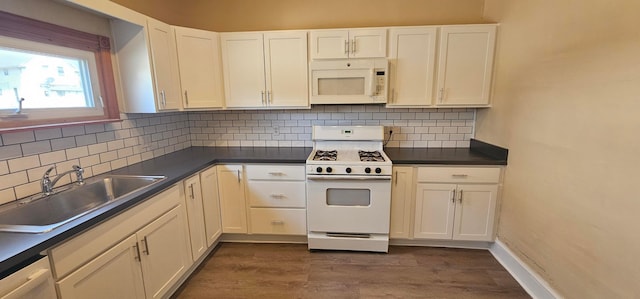 kitchen featuring dark countertops, white appliances, a sink, and tasteful backsplash