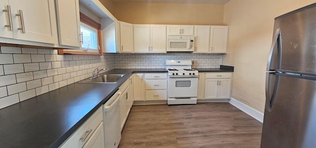 kitchen with dark countertops, white appliances, a sink, and dark wood-style flooring