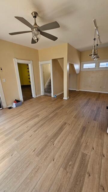 2402 E Ave, Columbus, OH 43202 - unfurnished living room with wood-type flooring, ceiling fan, and stairway