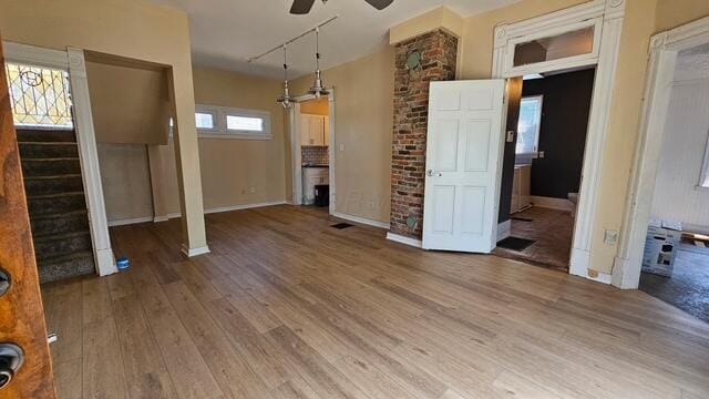 2402 E Ave, Columbus, OH 43202 - unfurnished living room with ceiling fan, wood finished floors, stairway, and track lighting