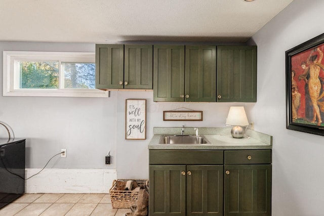 clothes washing area featuring sink, light tile patterned floors, cabinets, and a textured ceiling