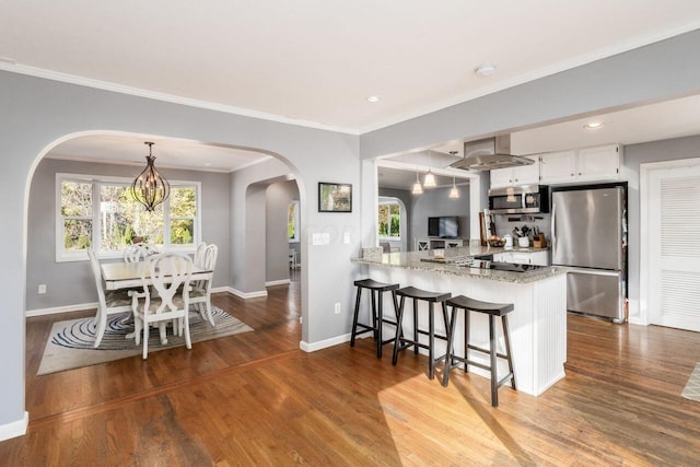 kitchen with kitchen peninsula, white cabinetry, wood-type flooring, and appliances with stainless steel finishes