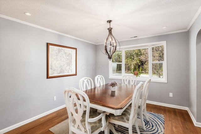 dining space featuring a textured ceiling, a chandelier, dark hardwood / wood-style floors, and ornamental molding