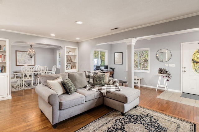 living room featuring wood-type flooring, crown molding, and built in shelves