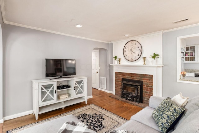 living room with wood-type flooring, a wood stove, and ornamental molding