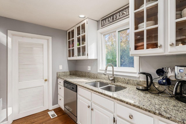 kitchen with dark hardwood / wood-style flooring, white cabinets, light stone counters, sink, and dishwasher