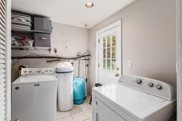 laundry area with electric panel, light tile patterned floors, and washer and dryer