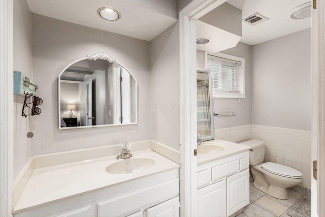 bathroom with tile patterned floors, vanity, tile walls, and toilet