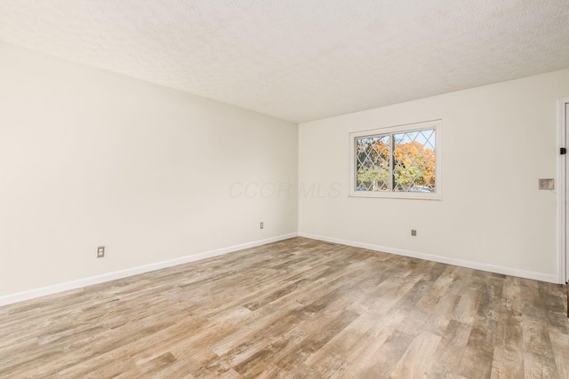 spare room with a textured ceiling and light wood-type flooring