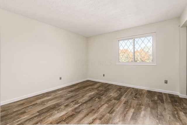 empty room with dark hardwood / wood-style flooring and a textured ceiling