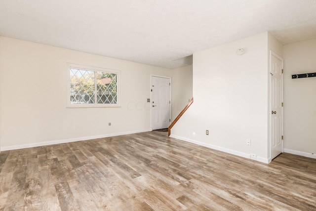 empty room with a textured ceiling and light hardwood / wood-style floors