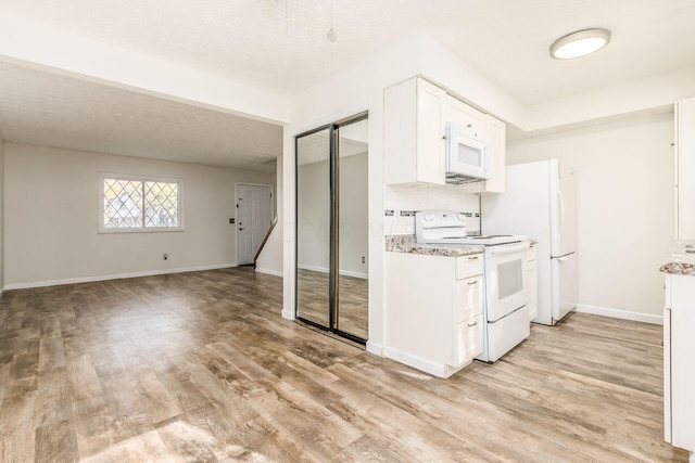 kitchen with white cabinetry, light stone counters, light hardwood / wood-style flooring, a textured ceiling, and white appliances