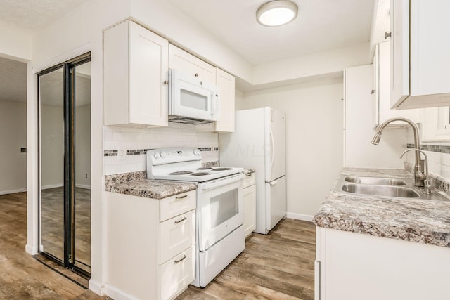 kitchen featuring white appliances, light hardwood / wood-style floors, white cabinetry, and sink