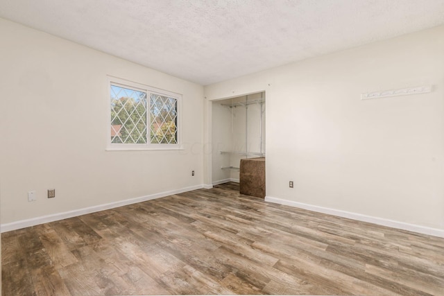 unfurnished bedroom featuring wood-type flooring, a textured ceiling, and a closet