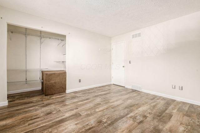 unfurnished bedroom with wood-type flooring, a textured ceiling, and a closet