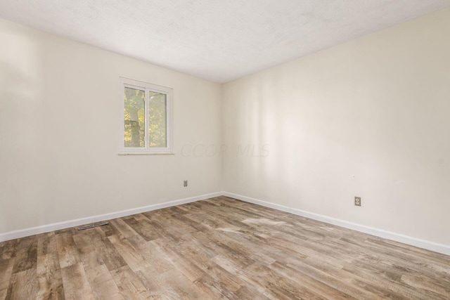 unfurnished room with a textured ceiling and light hardwood / wood-style floors