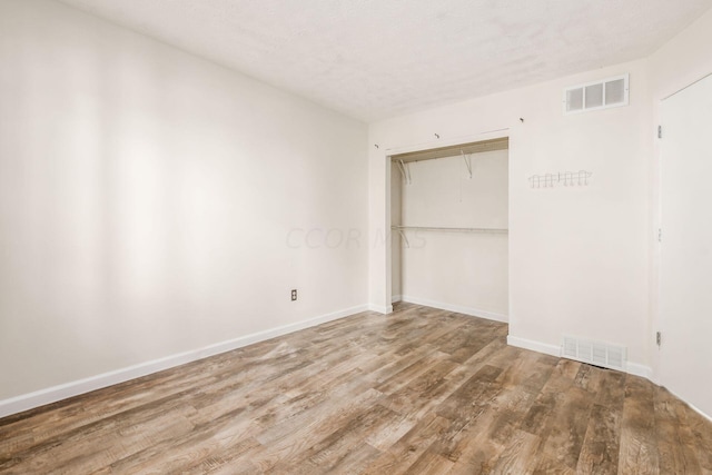 unfurnished bedroom with a closet, hardwood / wood-style floors, and a textured ceiling