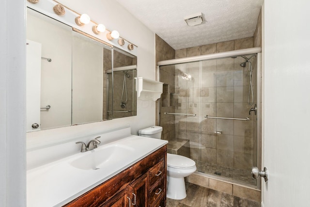 bathroom with hardwood / wood-style floors, an enclosed shower, a textured ceiling, toilet, and vanity