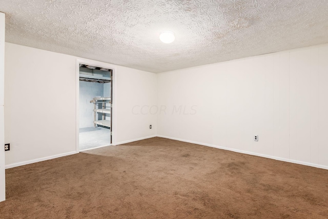 spare room featuring dark carpet and a textured ceiling