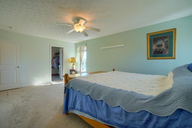 bedroom featuring carpet, a walk in closet, ceiling fan, a textured ceiling, and a closet