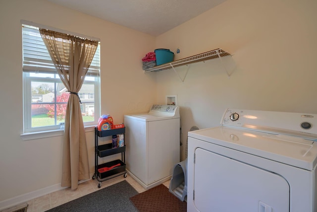 clothes washing area with washer and dryer, light tile patterned floors, and a textured ceiling