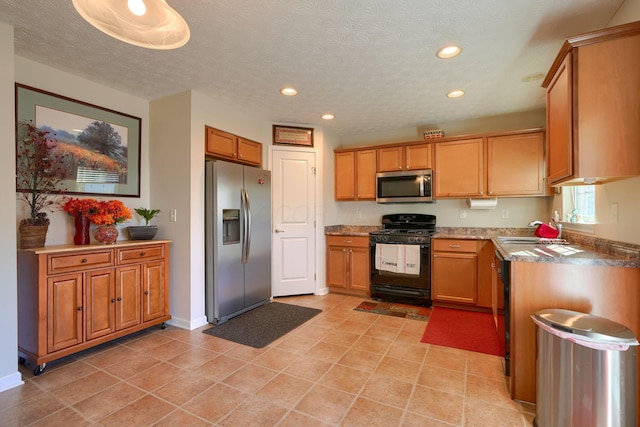 kitchen with sink, light tile patterned flooring, stainless steel appliances, and a textured ceiling