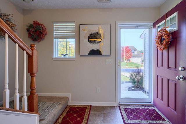 tiled entryway featuring a textured ceiling