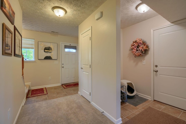 foyer entrance with light tile patterned flooring and a textured ceiling