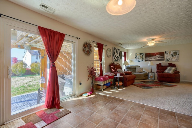 carpeted living room featuring a wealth of natural light, ceiling fan, and a textured ceiling