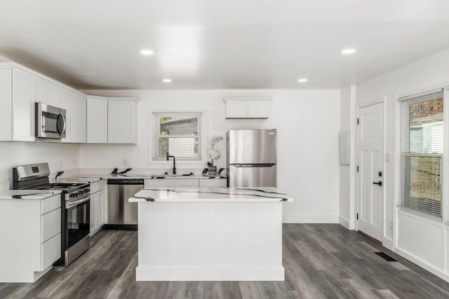 kitchen featuring a kitchen island, dark hardwood / wood-style flooring, a healthy amount of sunlight, and appliances with stainless steel finishes