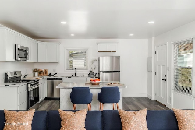 kitchen featuring stainless steel appliances, sink, white cabinets, dark hardwood / wood-style floors, and a kitchen island