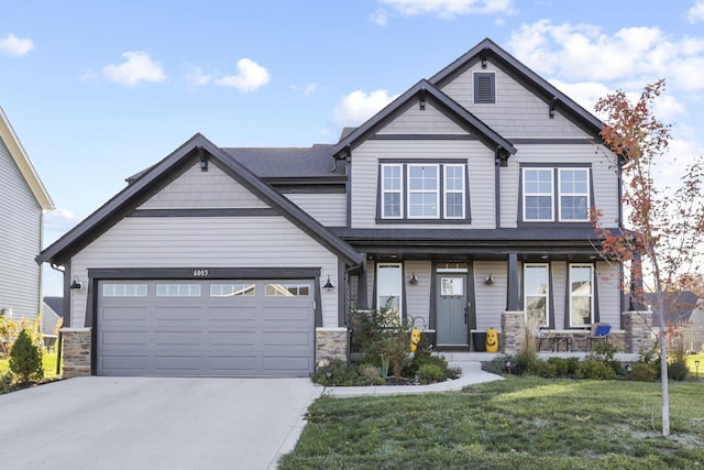 craftsman inspired home featuring covered porch, a garage, and a front lawn