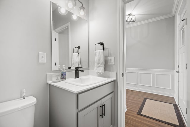 bathroom with wood-type flooring, vanity, toilet, and crown molding