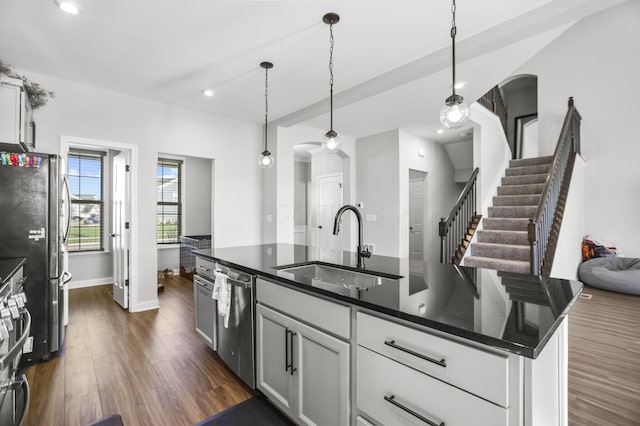 kitchen featuring dark wood-type flooring, sink, hanging light fixtures, an island with sink, and appliances with stainless steel finishes