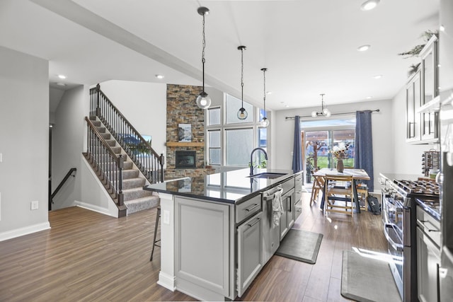 kitchen with sink, stainless steel appliances, dark wood-type flooring, a breakfast bar, and a center island with sink