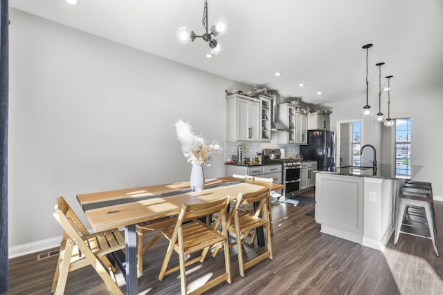 dining area featuring sink, dark hardwood / wood-style floors, and an inviting chandelier