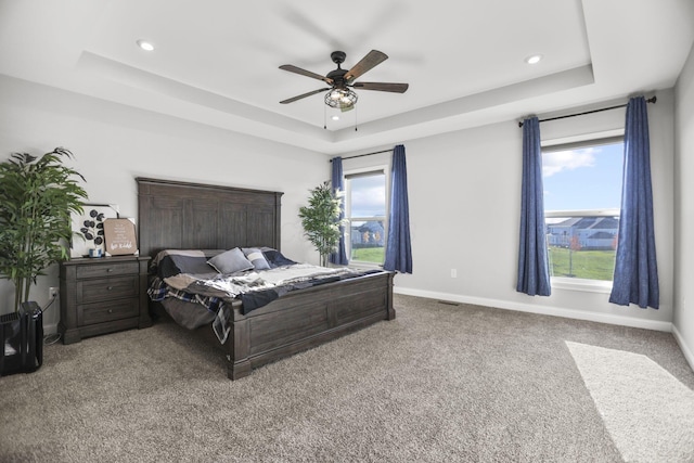 bedroom featuring carpet floors, a tray ceiling, and ceiling fan